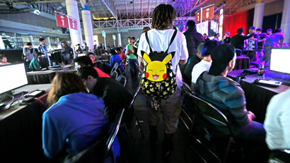 A visitor with a Pokemon backpack walks through a gaming area at the Major League Gaming World Finals in New Orleans, Friday, Oct. 16, 2015. Thousands of people are converging on New Orleans this weekend for the tournament. Players from around the world are competing in such games as Call of Duty: Advanced Warfare and Dota 2. The event started Friday and goes through Sunday at the convention center. (AP Photo/Gerald Herbert)