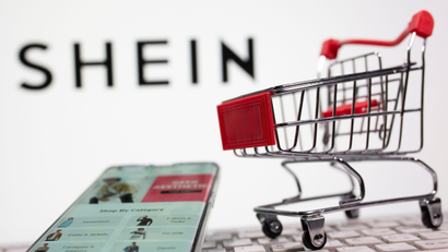 A keyboard and a shopping cart are seen in front of a displayed Shein logo in this illustration picture