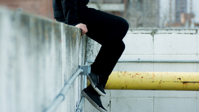 Young person sitting on a wall.