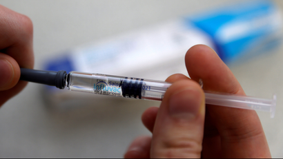 A person holds a syringe with a flu vaccine pre-loaded into it.