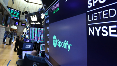A screen displays the company logo and trading info for Spotify on the floor at the NYSE in New York