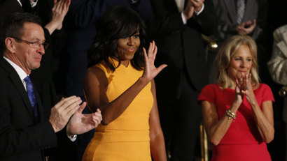 U.S. first lady Michelle Obama waves as she stands between Connecticut Governor Dannel Malloy (L) and Vice President Biden's wife Dr. Jill Biden (R) as they attend U.S. President Barack Obama's State of the Union address to a joint session of Congress in Washington, January 12, 2016.