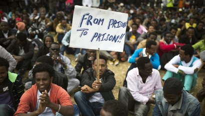 An African migrant holds a placard at Tel Aviv's Levinsky park, January 9, 2014, on the fifth consecutive day of protests against Israel's detention policy toward migrants it sees as illegal job-seekers. Israel passed a law three weeks ago allowing for indefinite detention of migrants without valid visas while it pursues efforts to persuade them to leave or enlist other countries to take them in.