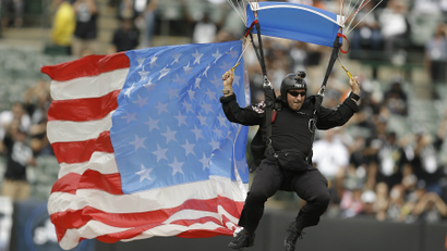 A man parachutes into O.co Coliseum with an American flag before an NFL football game between the Oakland Raiders and the Cincinnati Bengals in Oakland, California.
