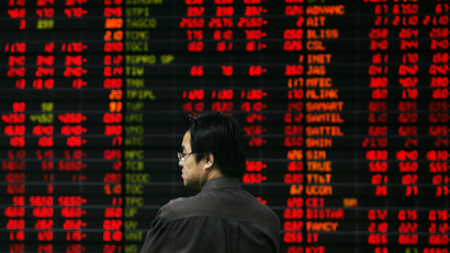 An investor looks at live market data on an electronic board at a stockbrokers office.