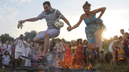 A couple jump over a campfire during a celebration of the traditional Ivana Kupala holiday near Kiev