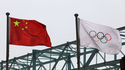 A Chinese flag flies next to an Olympic flag