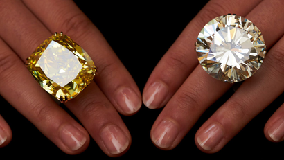 A model poses with a vivid yellow 100.09 carats diamond (L) and a 103.46 carats diamond ring during an auction preview at Sotheby's in Geneva May 7, 2014. These items are expected to reach between CHF 13,250,000 to 22,250,000 (USD 15,000,000 to 25,000,000) and CHF 3,100,00 and 4,450,000 (USD 3,500,00 to 5,000,000) when they go on sale May 13, 2014 in Geneva.