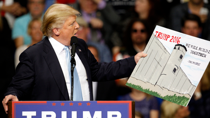 U.S. Republican presidential candidate Donald Trump holds a sign supporting his plan to build a wall between the United States and Mexico that he borrowed from a member of the audience at his campaign rally in Fayetteville, North Carolina March 9, 2016. Trump was interrupted repeatedly by demonstrators during his rally.
