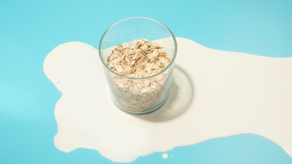 A small glass filled with oats on a blue and white background.