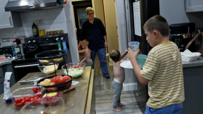 Rachel Newman herds her twin boys as her oldest, Benny, 9, brings his dinner dishes into the kitchen at the Newman home in Pitman, New Jersey, U.S., September 10, 2020.