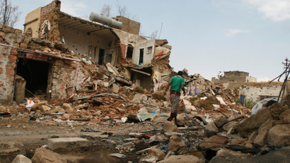 A man walks by a destroyed house