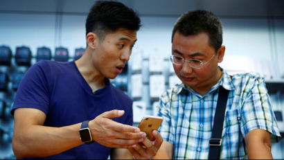 A staff member (L) explains Apple's new iPhone 7 to a customer at an Apple store in Beijing, China