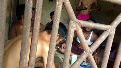 In this Saturday, Nov. 22, 2014 photo, Thai and Burmese fishing boat workers sit inside a cell at the compound of a fishing company in Benjina, Indonesia. The imprisoned men were considered slaves who might run away. They said they lived on a few bites of rice and curry a day in a space barely big enough to lie down, stuck until the next trawler forces them back to sea.