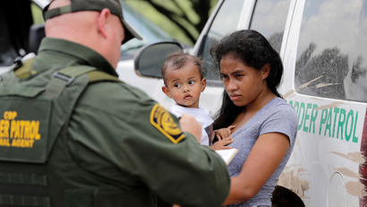 a mother migrating from Honduras holds her 1-year-old child as surrendering to U.S. Border Patrol agents after illegally crossing the border, near McAllen, Texas.