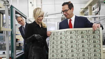 Treasury Secretary Steven Mnuchin, right, shows his wife Louise Linton a sheet of new $1 bills