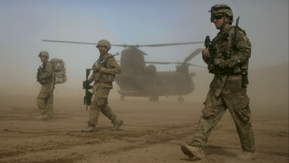 US soldiers walking in front of a helicopter.