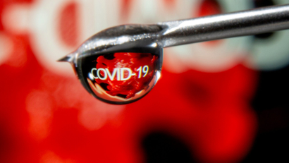 The word "COVID-19" is reflected in a drop on a syringe needle in this illustration taken November 9, 2020.