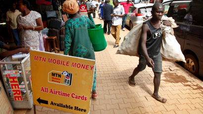 People walking on the streets of Kampala in Uganda past an MTN mobile money sign
