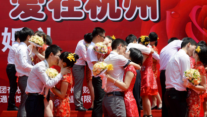 Couples kiss as they participate in a mass wedding ceremony in Hangzhou, Zhejiang province May 19, 2013. According to local media, a total of 80 couples attended the ceremony on Sunday. The characters collectively read: "Love in Hangzhou". REUTERS/Stringer