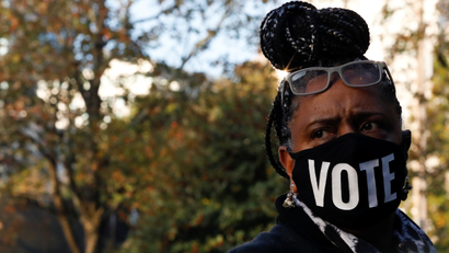 A woman wears a mask that says "VOTE"