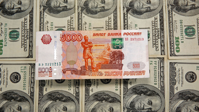 A ruble note on top of a layer of 100-dollar bills.