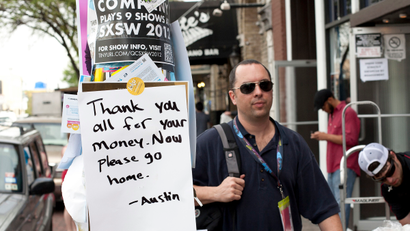 A man walks next to a sign posted on the street during the South by Southwest (SXSW) Music conference in Austin, Texas March 13, 2012. REUTERS/Julia Robinson (UNITED STATES - Tags: ENTERTAINMENT) - RTR2ZB2V