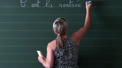 A woman writes on a blackboard.