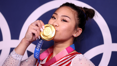 Gold medalist Sunisa (Suni) Lee of the United States kisses her medal in front of the Olympic rings.