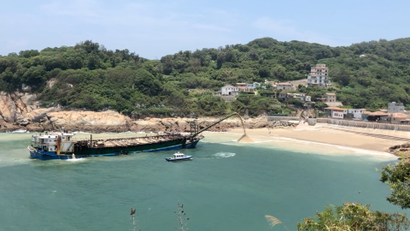 A Chinese sand dredging ship dumps sand back onto the Taiwanese coast after being caught by the Taiwanese Coast Guard.