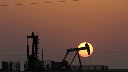 An oil pump works at sunset in the desert oil fields of Sakhir, Bahrain.