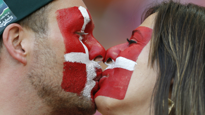 Denmark soccer fans kiss as they wait for the start of a match.