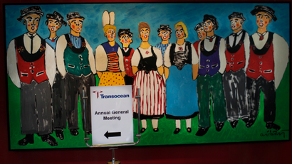 A sign for the Transocean annual general meeting in front of a painting of Swiss peasants.