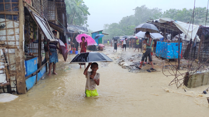 A boy plays in the flooded street after heavy monsoon rains triggered flooding at Kutapalong refugee camp in Bangladesh