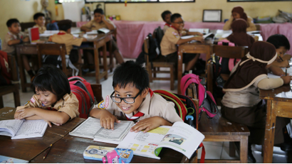 A student reacts to the camera as a teacher teaches the 2013 curriculum inside a classroom at Cempaka Putih district in Jakarta, October 15, 2014.