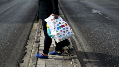 Woman holds a plastic bag with goods after exiting a Jumbo store in Athens