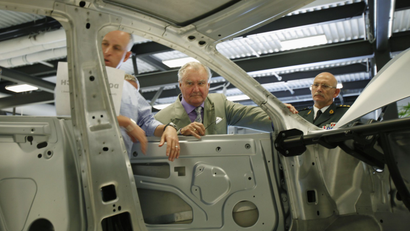 Prince Consort Henrik of Denmark (C) inspects the chassis of the Tesla Model S electric vehicle.