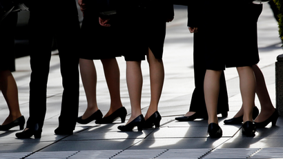 women office workers standing together wearing heels and skirts