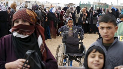 Syrian refugees stand in line at a refugee camp near the Jordanian border with Syria