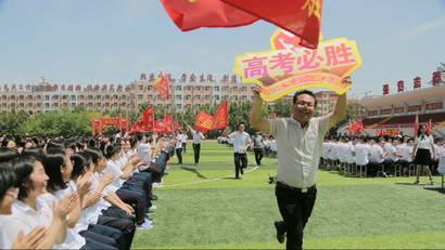 Teachers run with signs as they cheer for students at a rally ahead of the annual national college entrance examination, or "gaokao", at a high school in Hengshui, Hebei province, China May 24, 2018.