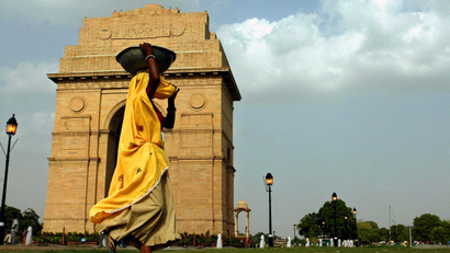 An Indian migrant labourer carries sand in front of India Gate in New Delhi