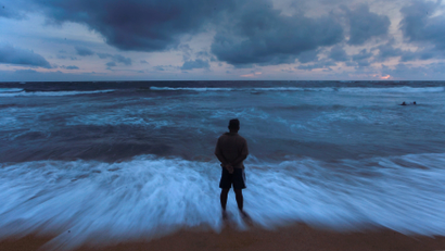 A man stands on a beach before the rain during the monsoon season in Colombo