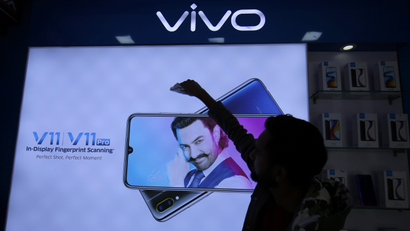 A man cleans a screen displaying a phone model of Chinese smartphone maker Vivo inside a shop in Ahmedabad
