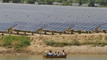 Security personnel sit in a boat as they patrol the premises of a newly inaugurated solar farm at Gunthawada village