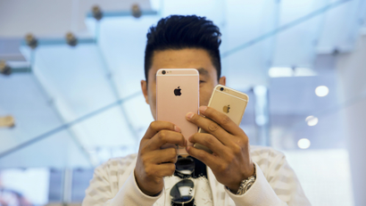 A man takes pictures as Apple iPhone 6s and 6s Plus go on sale at an Apple Store in Beijing