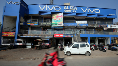 A scooterist rides past a shopping complex with the billboard of Chinese smartphone maker Vivo in Ahmedabad
