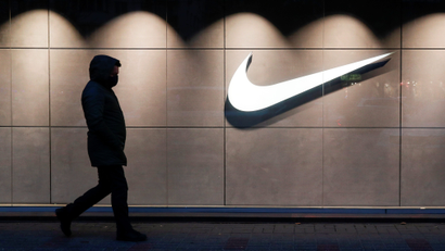 A photo shows a man's shadowy silhouette as he walks past a Nike store