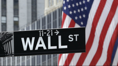 Wall Street sign with US flag behind it