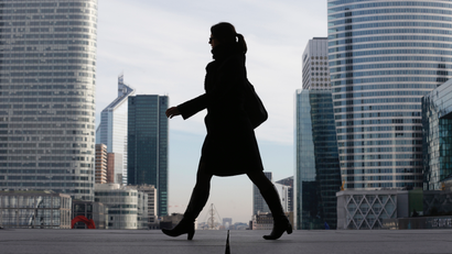 a businesswoman is silhouetted against Paris's financial district