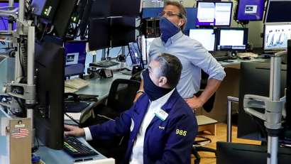 Traders wearing masks work, on the first day of in-person trading since the closure during the outbreak of the coronavirus disease (COVID-19) on the floor at the NYSE in New York